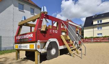 Eine große Spielzeugfeuerwehr steht auf einem Spielplatz.