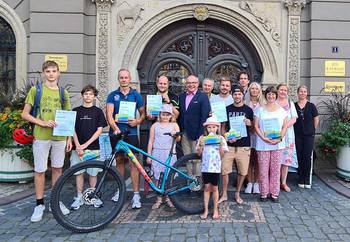 Gruppenbild mit Fahrrad vor dem Rathaus, öffnet größere Ansicht