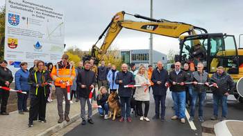 Ein Baustellenband wird durchggeschnitten und eine neu gebaute Straße freigegeben, öffnet größere Ansicht.