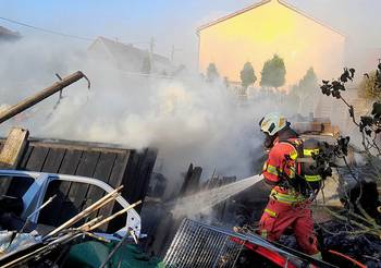 Ein Feuerwehrmann löscht einen Brand, öffnet größere Ansicht.