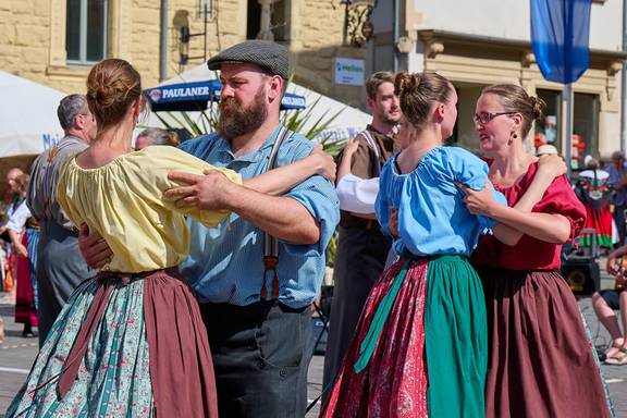 Tanzende Paare in bunter Tracht, öffnet größere Ansicht.