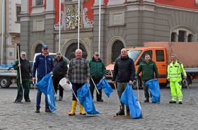 Gruppenbild mit Oberbürgermeister Knut Kreuch und weiteren Mitarbeitern vor dem Rathaus in Gotha. Sie halten Besen, Mülleimer und blaue Müllsäcke.