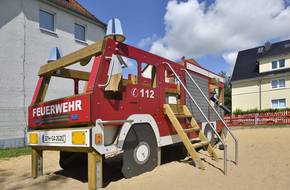 Eine große Spielzeugfeuerwehr steht auf einem Spielplatz.