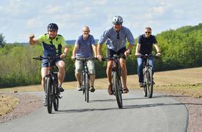 Oberbürgermeister Knut Kreuch und Bürgermeister Ulf Zillmann sowie Mitarbeiter der Stadtverwaltung fahren mit Fahrrädern auf einem neuen Radweg.