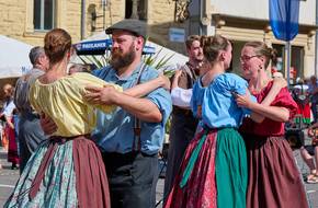 Tanzende Paare in bunter Tracht, öffnet größere Ansicht.