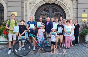 Gruppenbild mit Fahrrad vor dem Rathaus, öffnet größere Ansicht