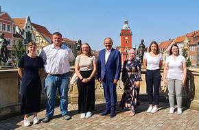 Gruppenfoto mit Rathaus im Hintergrund, öffnet größere Ansicht