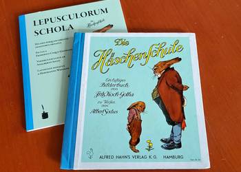 Eine lateinische Ausgabe von "Die Häschenschule" von Fritz Koch-Gotha und eine deutsche liegt auf einem Tisch.