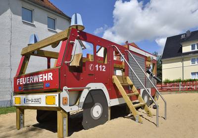 Eine große Spielzeugfeuerwehr steht auf einem Spielplatz.