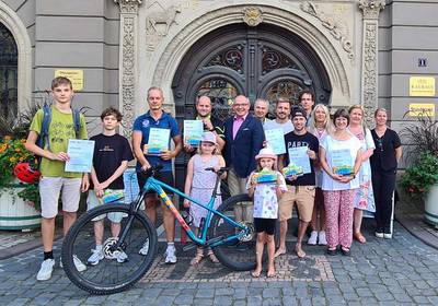 Gruppenbild mit Fahrrad vor dem Rathaus, öffnet größere Ansicht