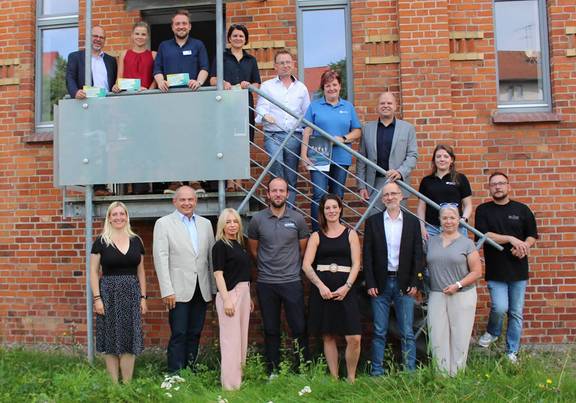 Gruppenbild von Unternehmerinnen und Unternehmern auf einer Außentreppe, öffnet größere Ansicht.