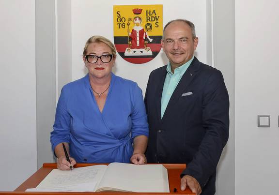 Knut Kreuch und Katrin Budde stehen vor dem Wappen der Stdat Gotha mit dem Goldenen Buch davor auf einem Tisch liegend, öffnet größere Ansicht.